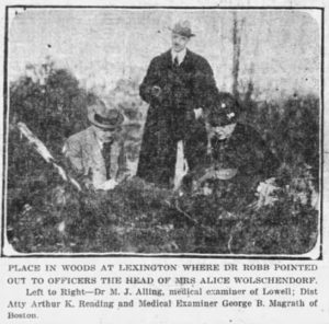 1923 news clipping: image of men examining site with caption "Place in woods at Lexington where Dr. Robb pointed out to officers the head of Mrs. Alice Wolschendorf; Left to Right - Dr. M. J. Ailing, medical examiner of Lowell; Dist. Atty. Arthur K. Reading and Medical Examiner George B. Mcgrath of Boston"